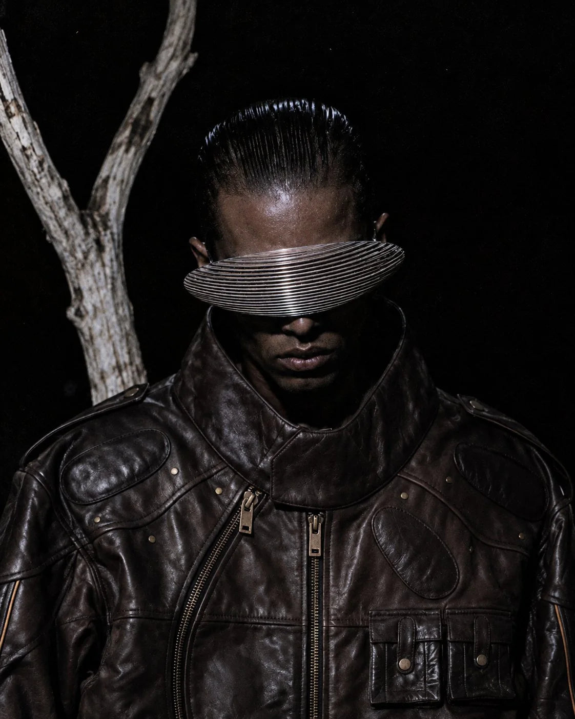 SVK-417 at night: the dark brown leather jacket with padded oval panels, brass studs and the curved front zip